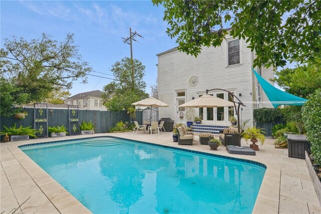 rear view of property with an outdoor living space, a patio, and a fenced in pool