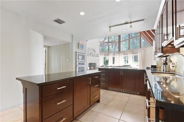 kitchen with rail lighting, stainless steel appliances, sink, dark brown cabinetry, and a center island