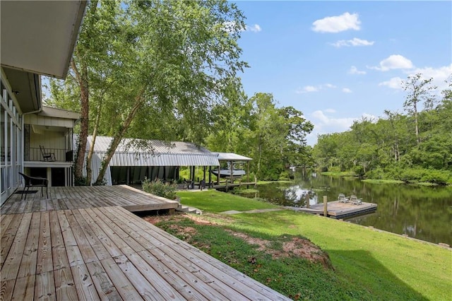 wooden deck with a water view, a lawn, and a boat dock