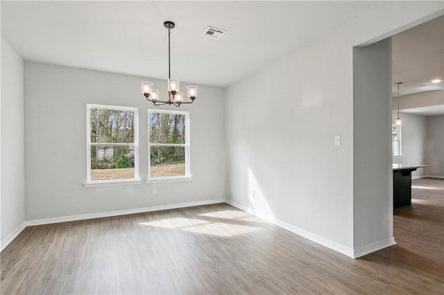 spare room with wood-type flooring and a notable chandelier