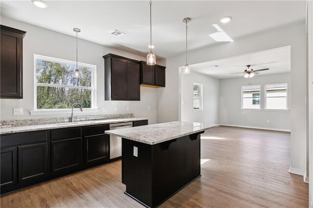 kitchen with ceiling fan, dishwasher, a kitchen island, sink, and a kitchen breakfast bar