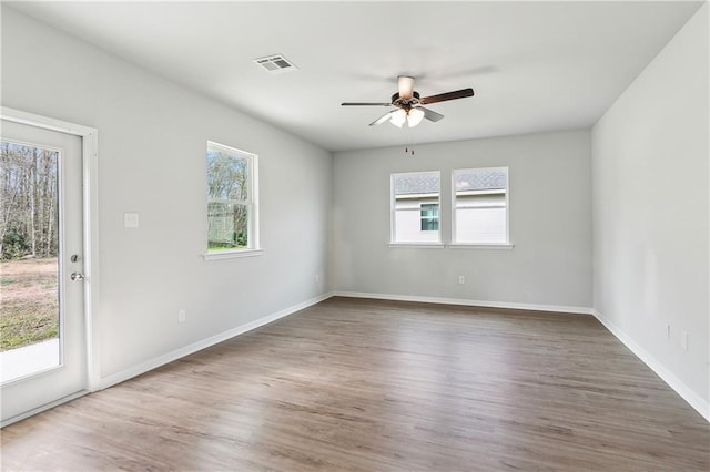 empty room featuring ceiling fan, dark hardwood / wood-style flooring, and a healthy amount of sunlight