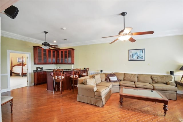 living room with crown molding, indoor bar, and hardwood / wood-style flooring