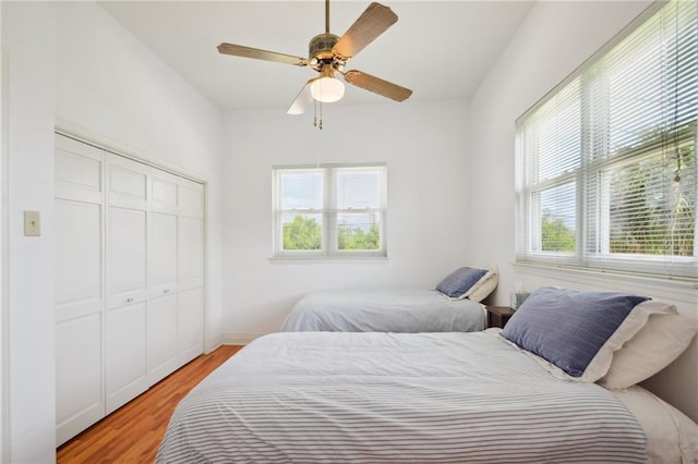 bedroom with a closet, light hardwood / wood-style floors, and ceiling fan