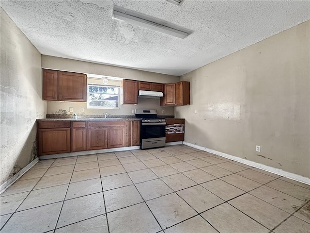 kitchen featuring a textured ceiling, sink, light tile patterned flooring, and stainless steel range oven