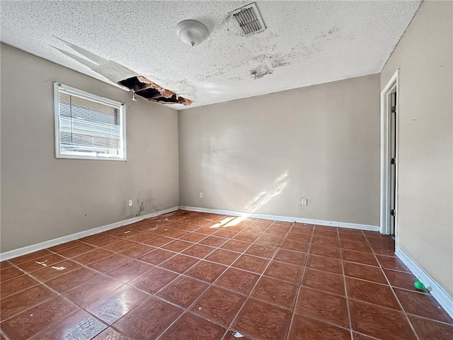 unfurnished room with dark tile patterned floors and a textured ceiling