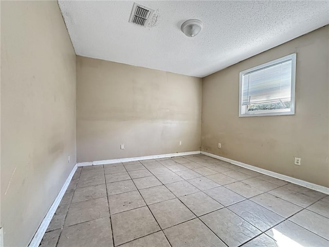 tiled spare room featuring a textured ceiling