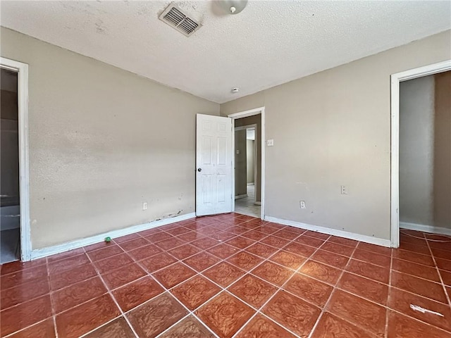 tiled spare room featuring a textured ceiling