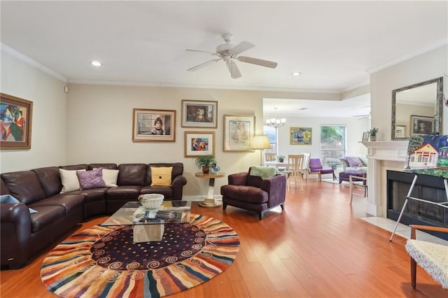 living room with hardwood / wood-style flooring, ceiling fan with notable chandelier, and ornamental molding