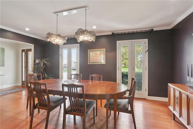 dining space featuring french doors, light wood-type flooring, crown molding, and an inviting chandelier