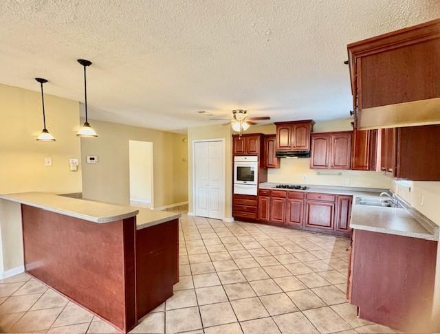 kitchen featuring sink, hanging light fixtures, ceiling fan, light tile patterned flooring, and kitchen peninsula