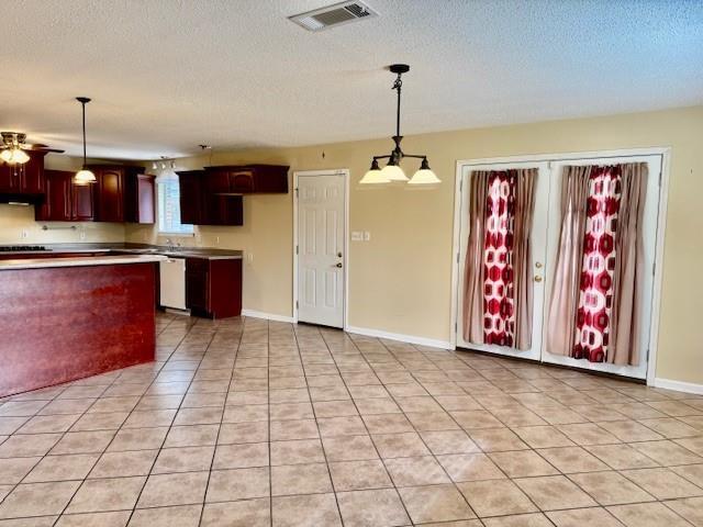 kitchen featuring dishwasher, light tile patterned flooring, pendant lighting, and a textured ceiling