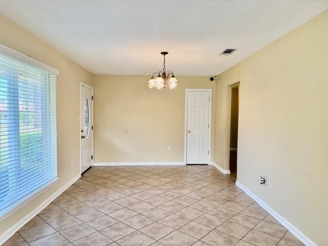 empty room featuring light tile patterned flooring and an inviting chandelier