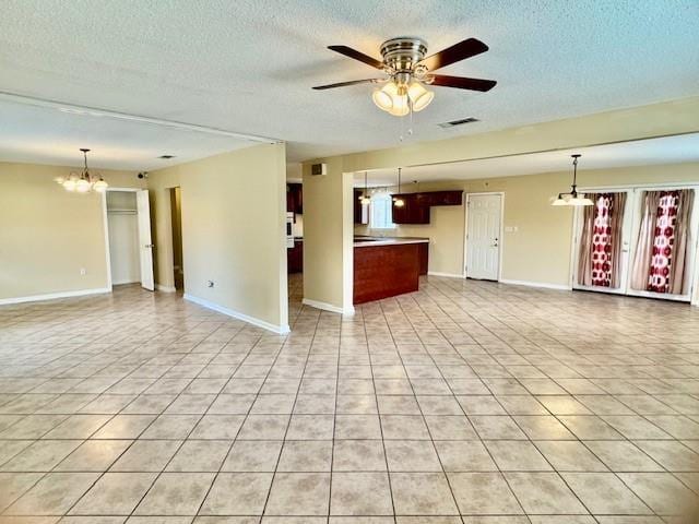 unfurnished living room with ceiling fan with notable chandelier, light tile patterned floors, and a textured ceiling