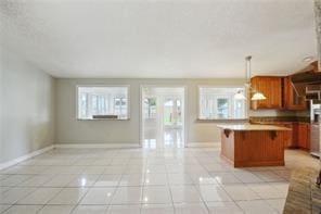 kitchen featuring hanging light fixtures, light tile patterned floors, and plenty of natural light