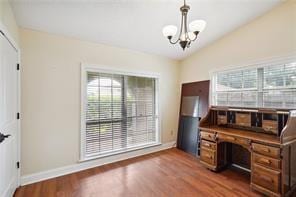 unfurnished office with hardwood / wood-style flooring, lofted ceiling, and an inviting chandelier