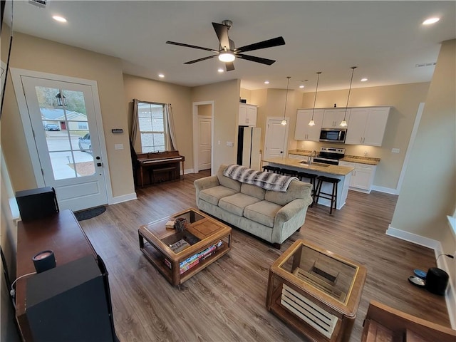 living room featuring ceiling fan, wood-type flooring, and sink