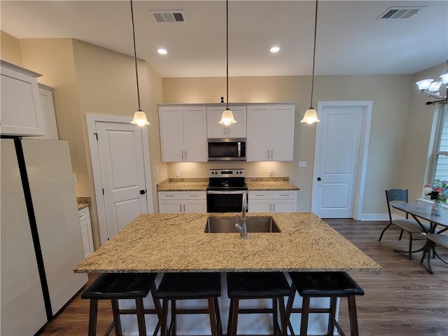 kitchen with pendant lighting, stainless steel appliances, a breakfast bar, and a kitchen island with sink