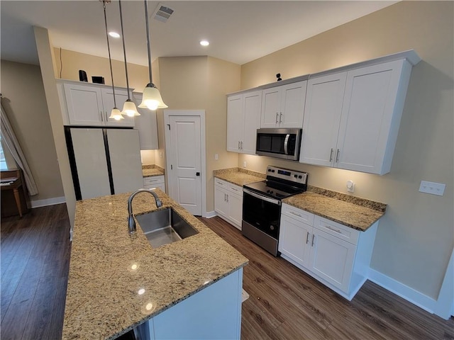 kitchen with pendant lighting, sink, appliances with stainless steel finishes, white cabinetry, and a center island with sink