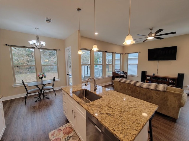 kitchen featuring pendant lighting, a kitchen island with sink, sink, and white cabinets