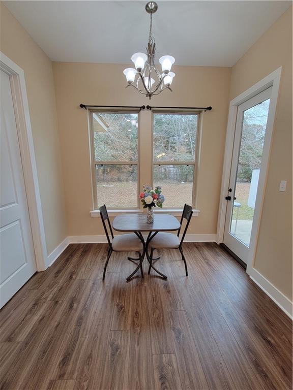 dining room with dark wood-type flooring and an inviting chandelier