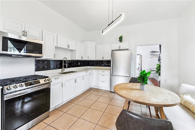 kitchen featuring appliances with stainless steel finishes, light tile patterned floors, white cabinetry, and sink