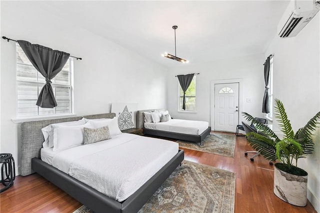 bedroom featuring dark hardwood / wood-style floors and a wall unit AC