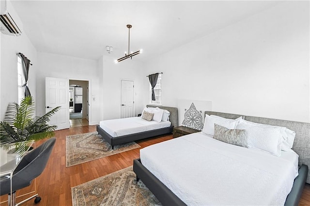 bedroom with hardwood / wood-style flooring, a wall unit AC, and an inviting chandelier