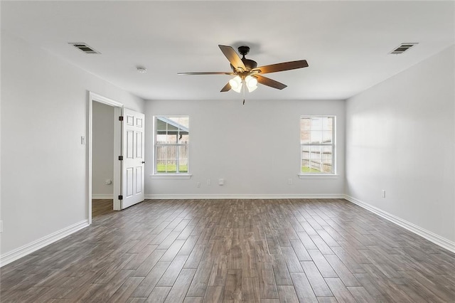 spare room featuring visible vents, a healthy amount of sunlight, dark wood-type flooring, and ceiling fan