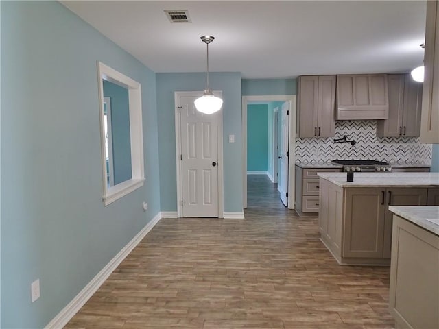 kitchen featuring decorative backsplash, light wood-type flooring, hanging light fixtures, and range