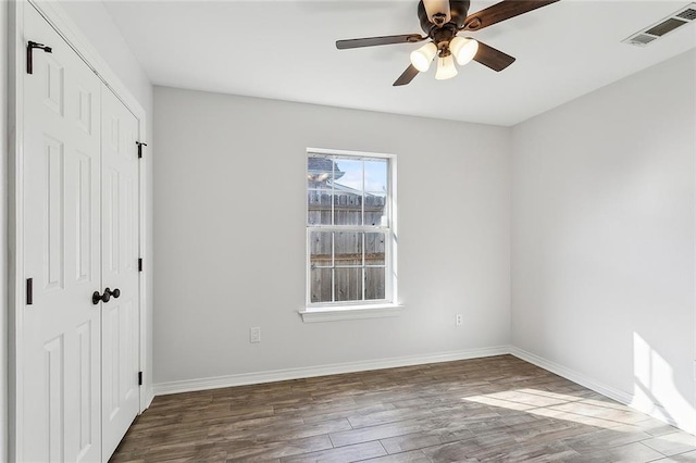 unfurnished bedroom with a closet, visible vents, baseboards, and wood finished floors