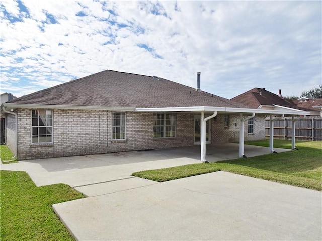 rear view of house featuring a patio, fence, a shingled roof, a lawn, and brick siding