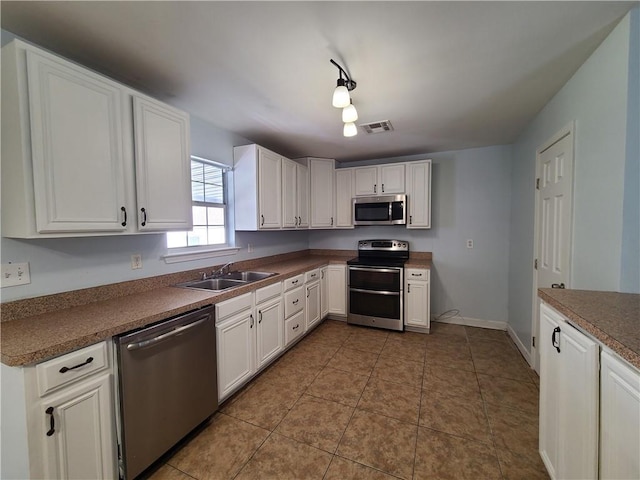 kitchen featuring sink, white cabinets, stainless steel appliances, and tile patterned flooring