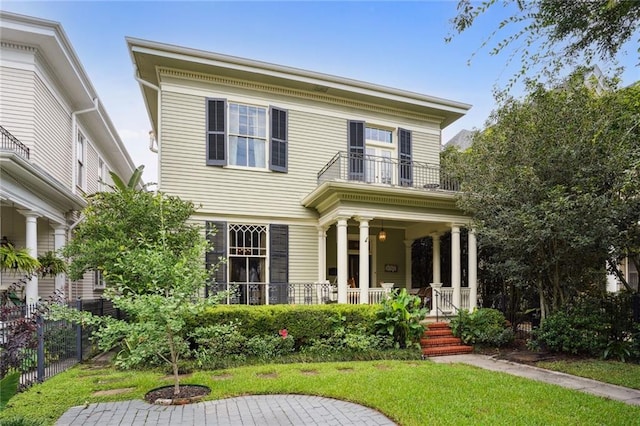 view of front of home featuring a balcony, a front yard, and covered porch