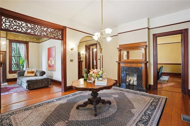 sitting room featuring hardwood / wood-style flooring, an inviting chandelier, and a fireplace