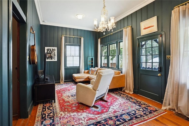 living area featuring ornamental molding, an inviting chandelier, and hardwood / wood-style flooring