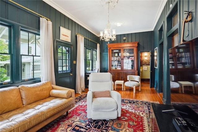 living area with wood-type flooring, crown molding, and a notable chandelier