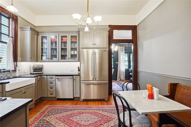 kitchen with sink, stainless steel appliances, gray cabinetry, and hanging light fixtures