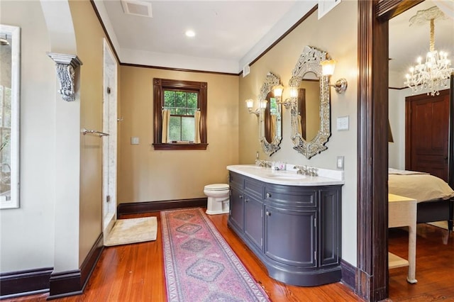 bathroom with a chandelier, toilet, vanity, and wood-type flooring