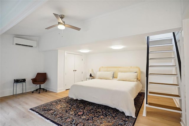 bedroom with a closet, a wall mounted AC, ceiling fan, and wood-type flooring