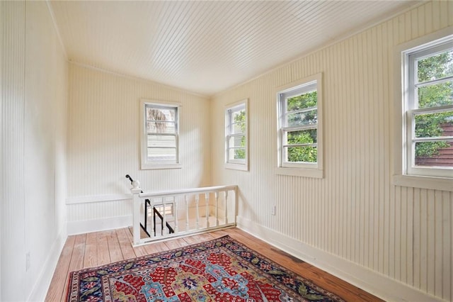 spare room with a healthy amount of sunlight, hardwood / wood-style floors, and ornamental molding