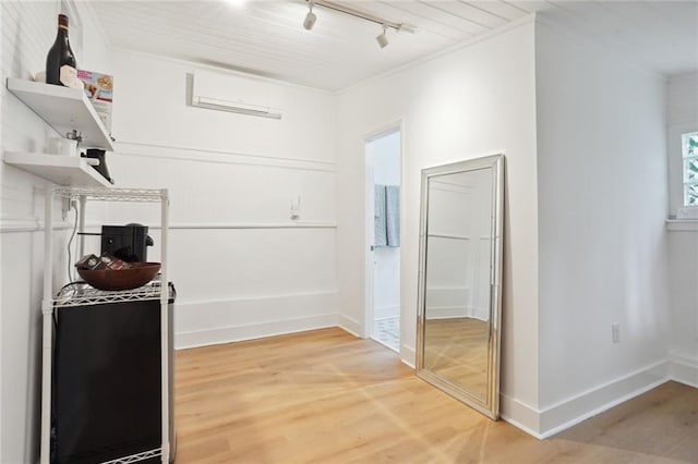 interior space with hardwood / wood-style floors, a wall unit AC, and rail lighting