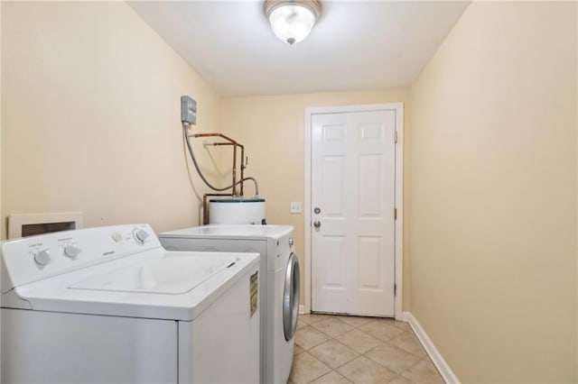 laundry area with water heater, washing machine and clothes dryer, and light tile patterned floors