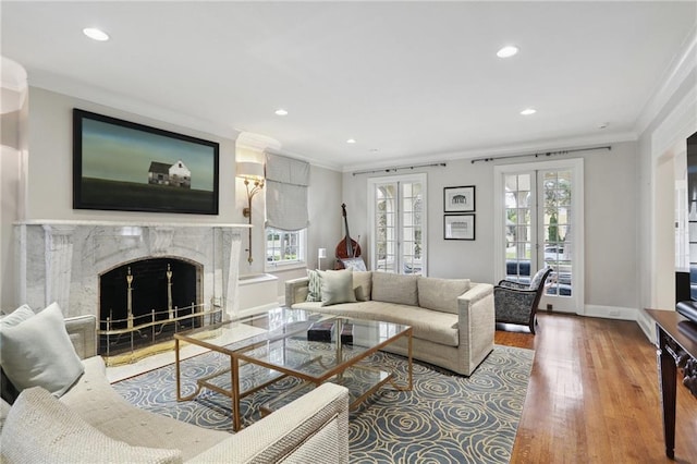 living room featuring plenty of natural light, ornamental molding, french doors, and a fireplace