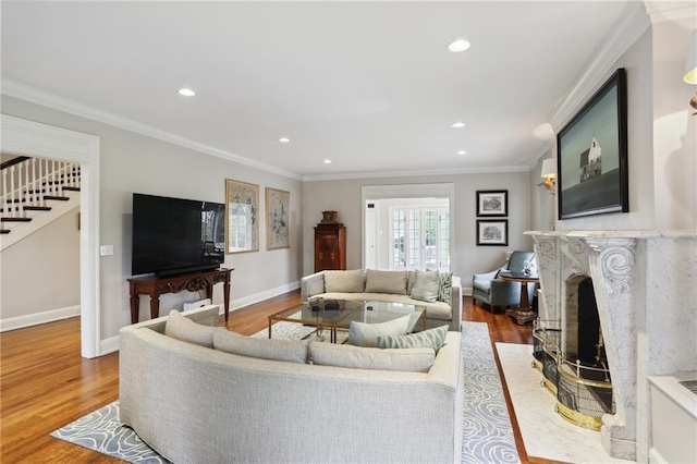 living room with wood-type flooring, a high end fireplace, and ornamental molding