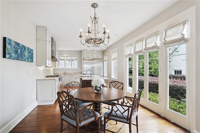 dining area with sink, a chandelier, and hardwood / wood-style flooring