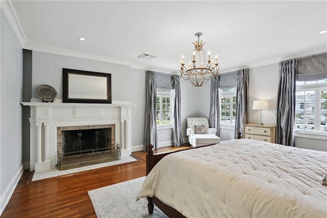 bedroom featuring a chandelier, dark hardwood / wood-style floors, crown molding, and a tiled fireplace