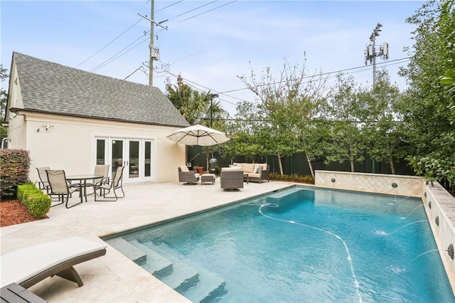 view of swimming pool with pool water feature, an outdoor living space, french doors, and a patio