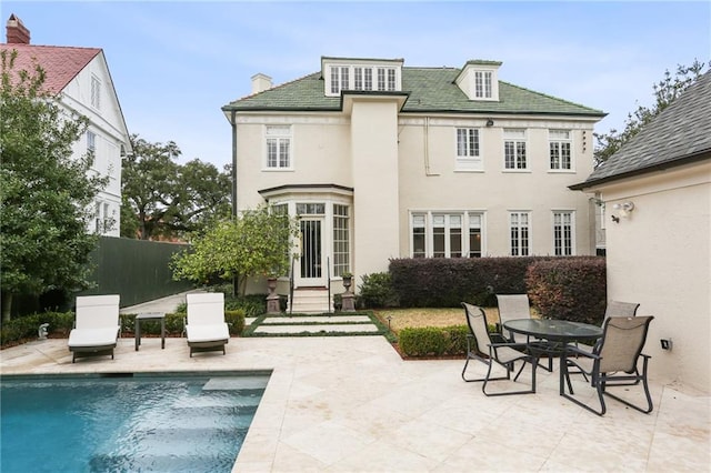 rear view of property with a fenced in pool and a patio