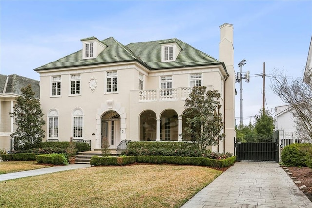 french country style house with a front lawn and a balcony